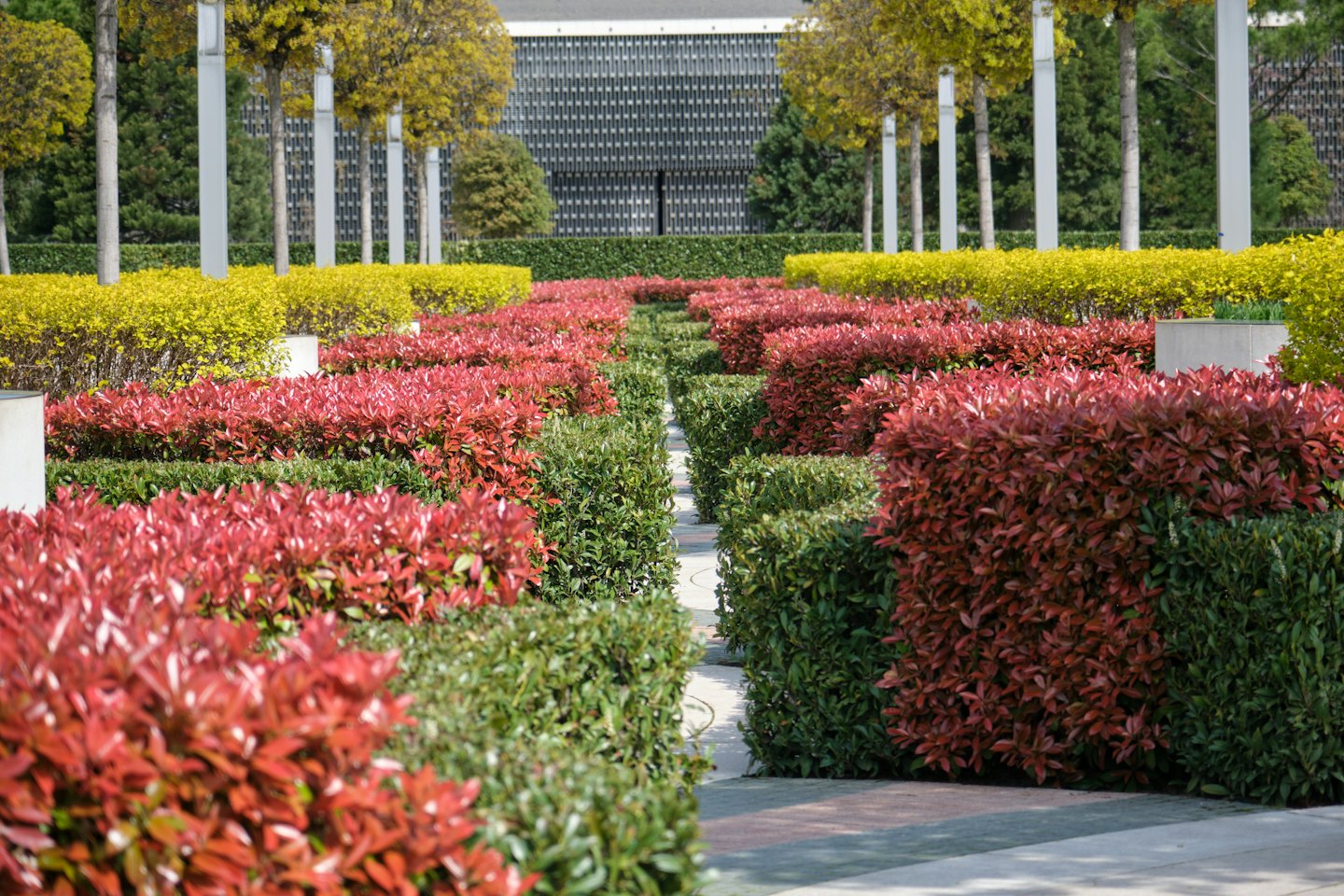 Manicured hedges and red shrubs line a structured formal garden.