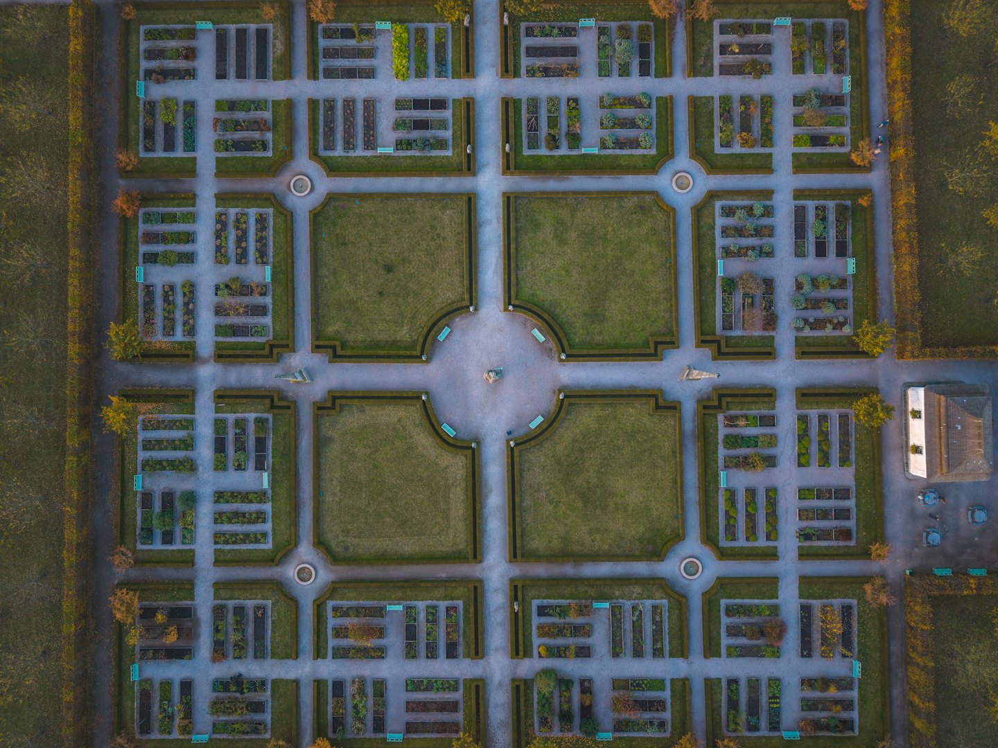 Symmetrical formal garden with manicured hedges and grey stone paths.